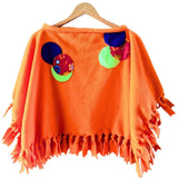 Orange Fleece poncho with tassels and colorful circular patches on a hanger - Parade Handmade