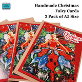 Three handmade Christmas fairy cards fanned out on a white background, with text reading 'Handmade Christmas Fairy Cards 3 Pack of A5 Size.' The cards feature a painted fairy in a red dress among green and blue holiday tree branches, with 'Christmas Wishes' written in white script on the front.