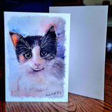 Complete view of a blank printed greeting card with a watercolor painting of a cat's face on a wooden surface by Nuala Brett-King - Parade Handmade