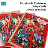 Three handmade Christmas fairy cards fanned out on a white background, with text reading 'Handmade Christmas Fairy Cards 3 Pack of A5 Size.' The cards feature a painted fairy in a red dress among green and blue holiday tree branches, with 'Christmas Wishes' written in white script on the front.